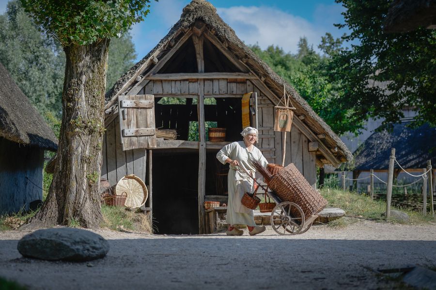 Mandenvlechter bij een middeleeuws huis