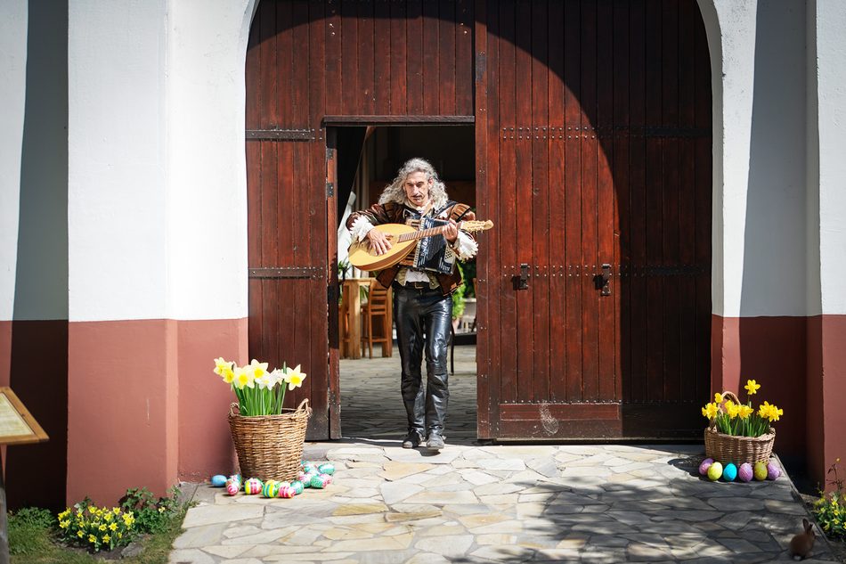 Troubadour met luit voor een houten poort
